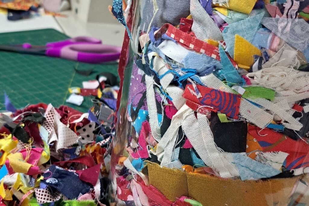 pote com micro retalhos de tecido sobre base de corte para patchwork